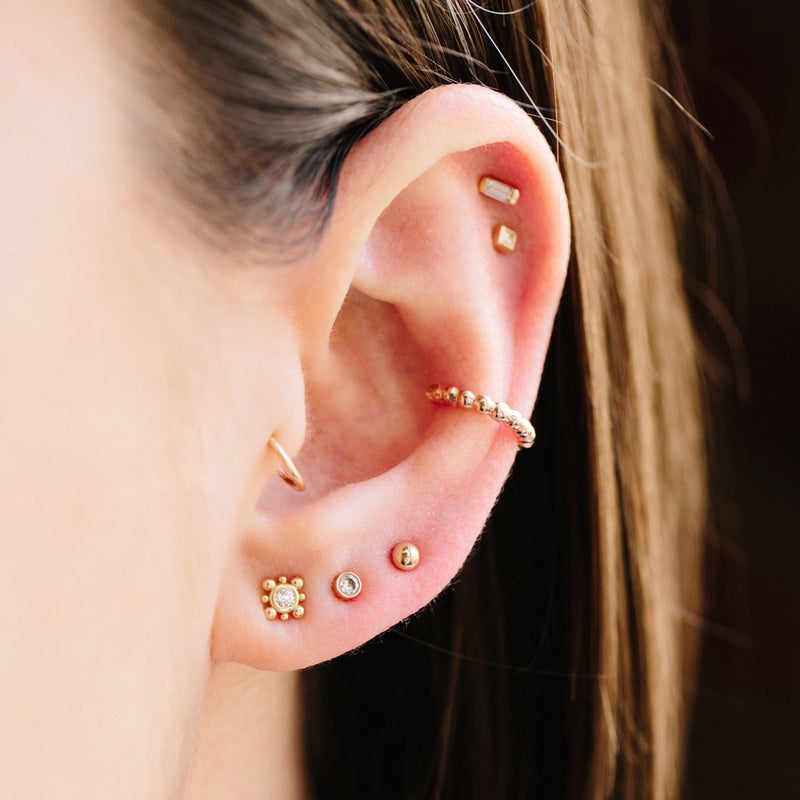 woman's ear wearing Zoë Chicco 14kt Gold Tiny Bead Diamond Starburst Earrings