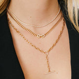 Close up of woman's neck wearing a Zoë Chicco 14k Gold Vintage Pavé Diamond Horsebit Link Medium Curb Chain Necklace layered with a diamond tennis necklace and a faux toggle necklace