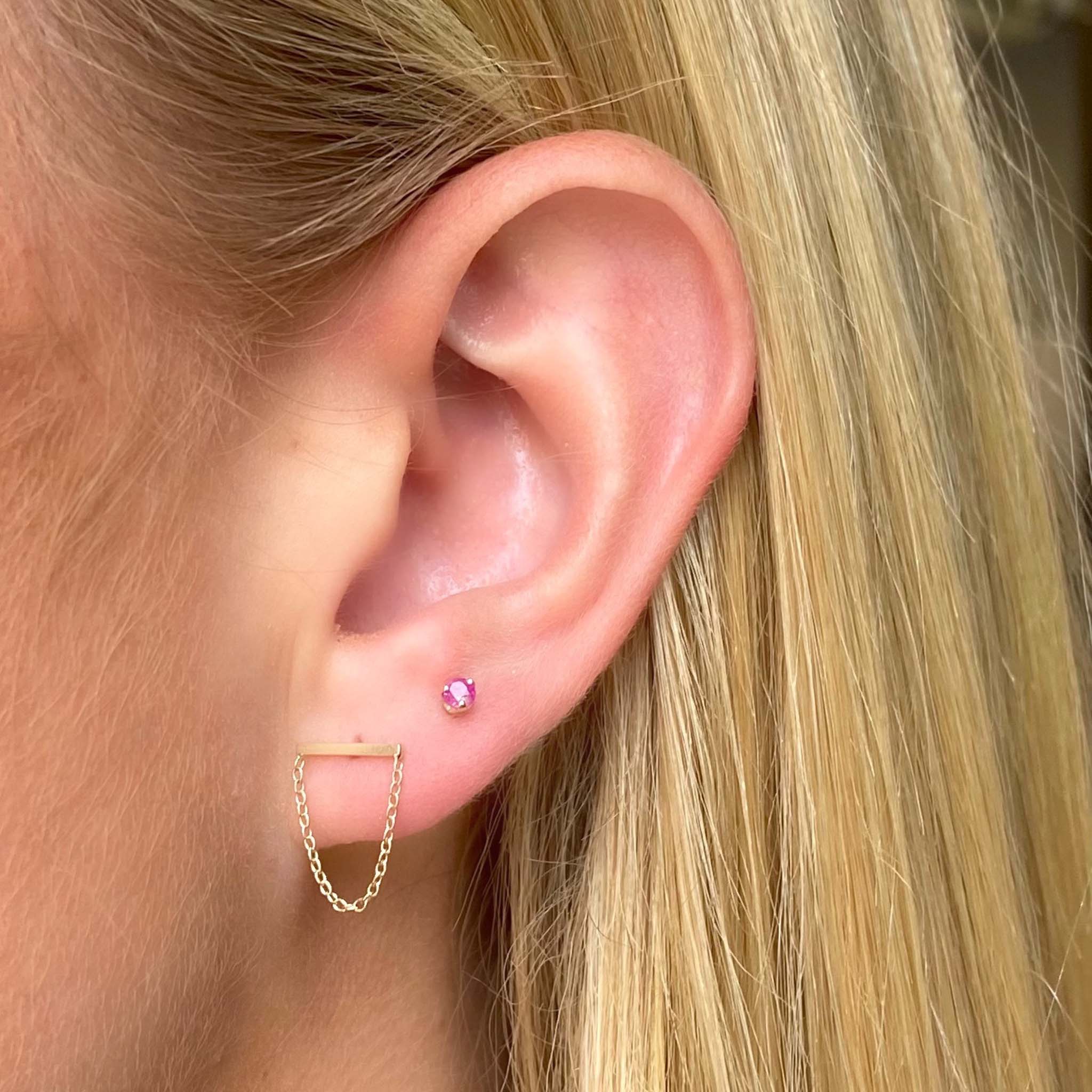 Woman's ear wearing Zoë Chicco 14kt Gold Chain Bar Stud Drop Earring with a Ruby Prong Stud