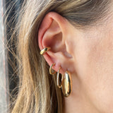 woman's ear wearing Zoë Chicco 14kt Gold Medium Wide Round Hoop Earring with a 10 Pave Diamond Medium Hoop, a Hinge Huggie Hoop, and a wide ear cuff