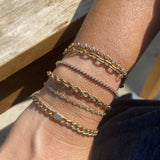 close up of woman's wrist resting on a wooden table wearing a Zoe Chicco 14kt gold large rope chain bracelet