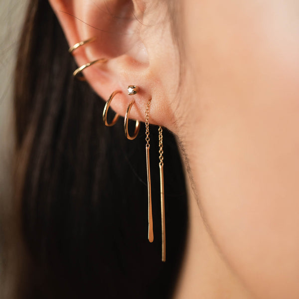 woman's ear wearing a Zoë Chicco 14k Yellow Gold Double Ear Cuff layered with a Thin Double Huggie Hoop and a Hammered Short Wire Threader Earring