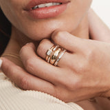 close up of a woman's hand wearing a Zoë Chicco 14k Gold 6 Baguette Diamond Open Ring layered with three other rings