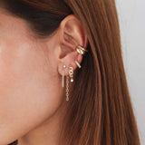 Woman's ear wearing three different earrings and a Zoë Chicco 14k Gold Beaded Ear Cuff with Diamond