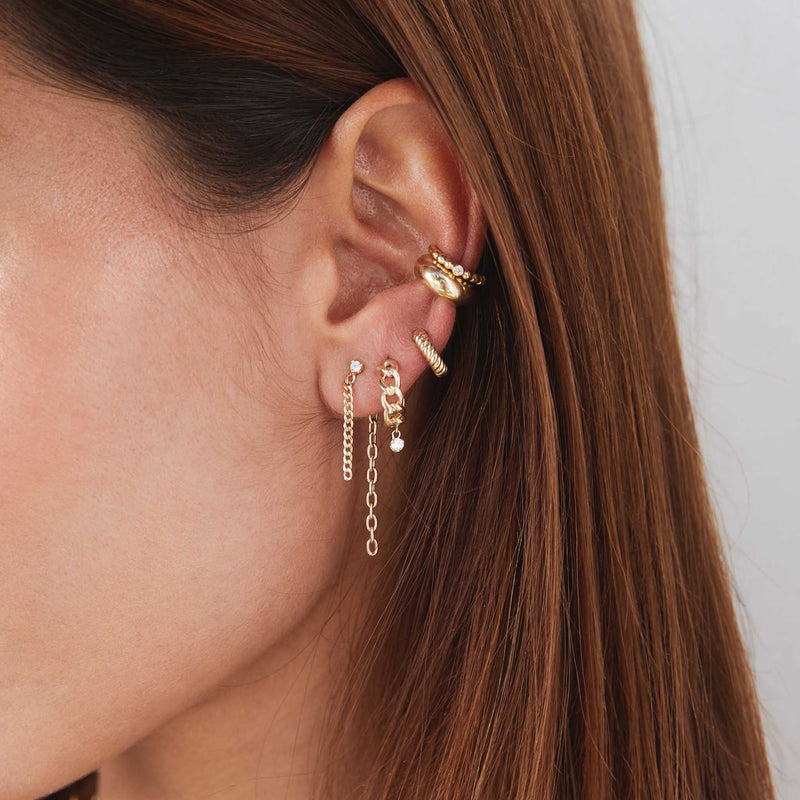 the side of a woman's head showing her wearing a Zoë Chicco 14k Gold Prong Diamond Mixed Chain Double Drop Earring layered with other gold and diamond earrings