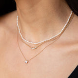 woman wearing a Zoë Chicco 14k Gold Rice Pearl Necklace layered with a Floating Diamond Solitaire Necklace and a 14k 5 Diamond Bezel Extra Small Curb Chain Necklace