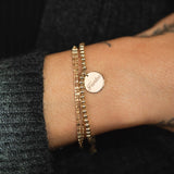 close up of woman's wrist wearing a Zoë Chicco 14k Gold Triple Strand Tube Bar Chain Bracelet