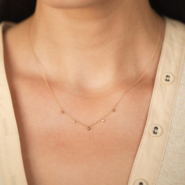 woman in a beige knit top wearing a Zoë Chicco 14k Gold Scattered Diamonds & Tiny Gold Beads Necklace
