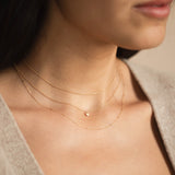 woman wearing a Zoë Chicco 14k Gold Adjustable Cable Chain Necklace layered with a Bar and Cable Chain Necklace and Itty Bitty Heart Padlock necklace