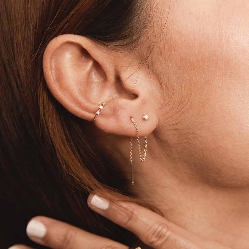 a woman's ear with a Single Zoë Chicco 14k Gold Prong Diamond Chain Threader Earring wrapped around and threaded through two piercings with a diamond ear cuff