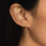 woman wearing a Zoë Chicco 14k Gold Baguette Diamond Hinge Huggie Hoop Earring layered with a 14k Tiny Bead Diamond Starburst Stud Earring in her second piercing
