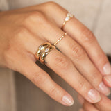 A woman's hand is wearing a stack of two half round bands with emerald and marquise shaped diamonds