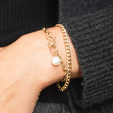 woman's wrist wearing a Zoë Chicco 14k Gold Medium Curb Chain Bracelet stacked with a Medium Oval Link Pearl Dangle Bracelet