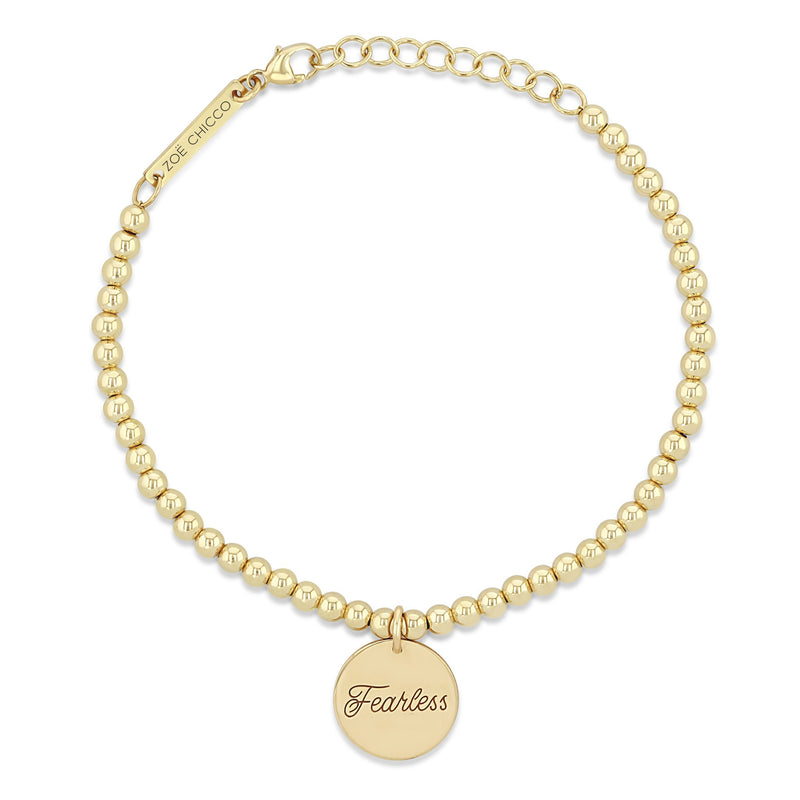 top down view of Zoë Chicco 14k Gold Bead Amore Charm Bracelet engraved with Fearless