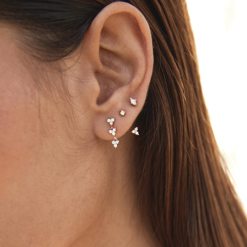 close up of a woman's ear wearing a Zoë Chicco 14k Gold Linked Diamond Trio Drop Earring with a Diamond Stud Jacket Earring and a Marquise Diamond Stud