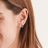 close up of a woman's ear wearing a Zoë Chicco 14k Gold 3 Graduated Prong Diamond Curve Stud Earring in her third piercing layered with a Knife Edge Hoop and a Diamond Stud Jacket Earring