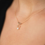 close up of a woman wearing a Zoë Chicco 14k Gold Tiny Pearl & Diamond Mobile Bead Necklace