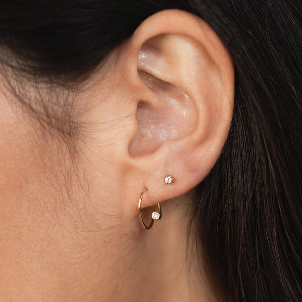close up of a woman's ear wearing a Zoë Chicco 14k Gold Small Diamond Swirl Hoop Earring