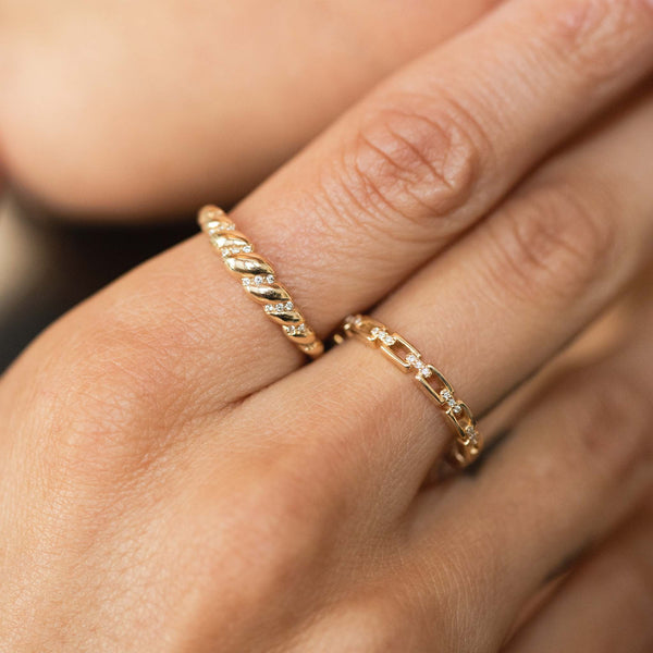 woman resting her hand on her face while wearing a Zoë Chicco 14k Gold Diamond Croissant Ring on her pointer finger and a 14k Diamond Rectangle Link Ring on her middle finger