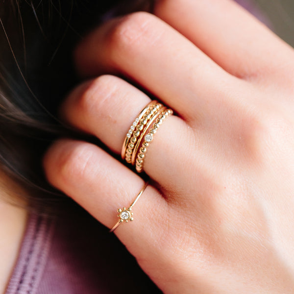 close up of hand with a mix of 5 diamond and gold beaded rings